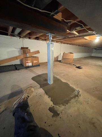 An immaculate interior crawl space view in Siren, WI showing a heavy-duty galvanized steel SmartJack support column cleanly installed on a new concrete pad to reinforce a large wooden floor beam.