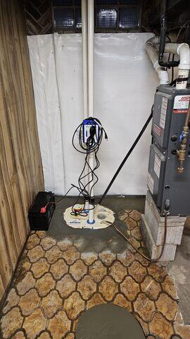 An immaculate basement utility room featuring a newly installed TripleSafe sump pump system with clear covers, dual PVC pipes, a standby battery backup box, and bright white CleanSpace vapor barrier liners on the walls in Carlton, MN.