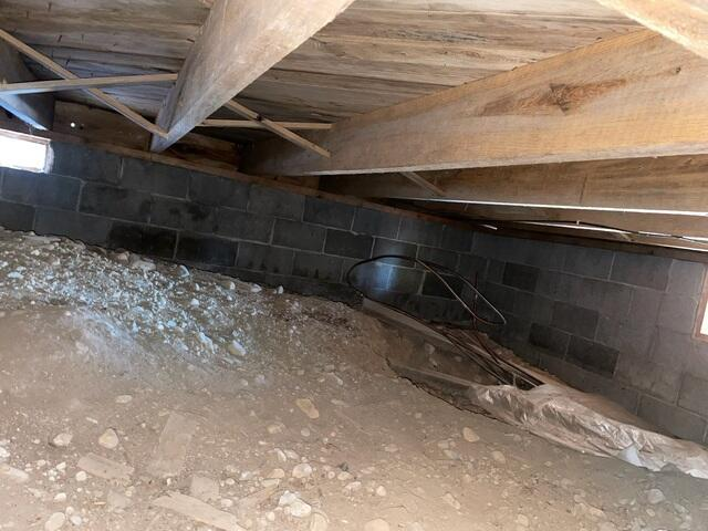 An unfinished basement crawl space showing open dirt flooring and concrete block foundation walls in Mercer, WI before encapsulation.