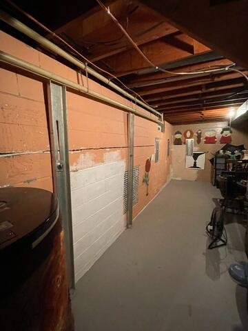 A view along an orange-painted basement block wall in Washburn, WI featuring several vertical steel channel anchor beams reinforcing a horizontal structural crack.