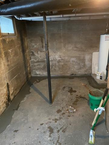 An immaculate basement floor showing a freshly poured concrete perimeter trench patch covering an installed WaterGuard drainage system along the wall in Carlton, MN.
