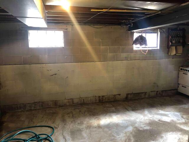A wide view of a clean concrete basement featuring newly installed vertical steel PowerBrace beams and clean white molding along the floor perimeter in Esko, MN.
